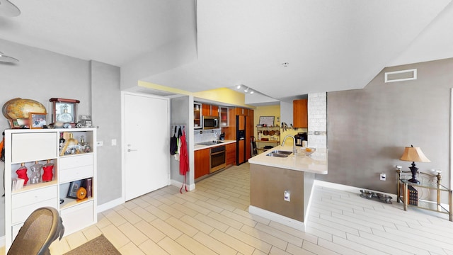 kitchen with appliances with stainless steel finishes, kitchen peninsula, and sink