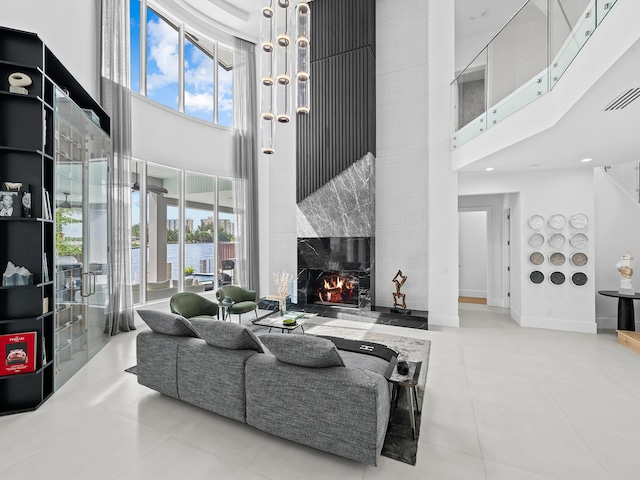 tiled living area with visible vents, a high ceiling, a premium fireplace, and a wealth of natural light