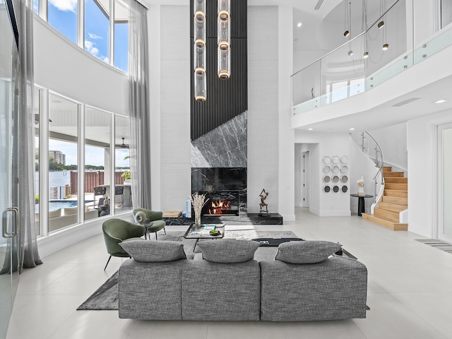 living room featuring a high end fireplace, visible vents, a towering ceiling, and stairs