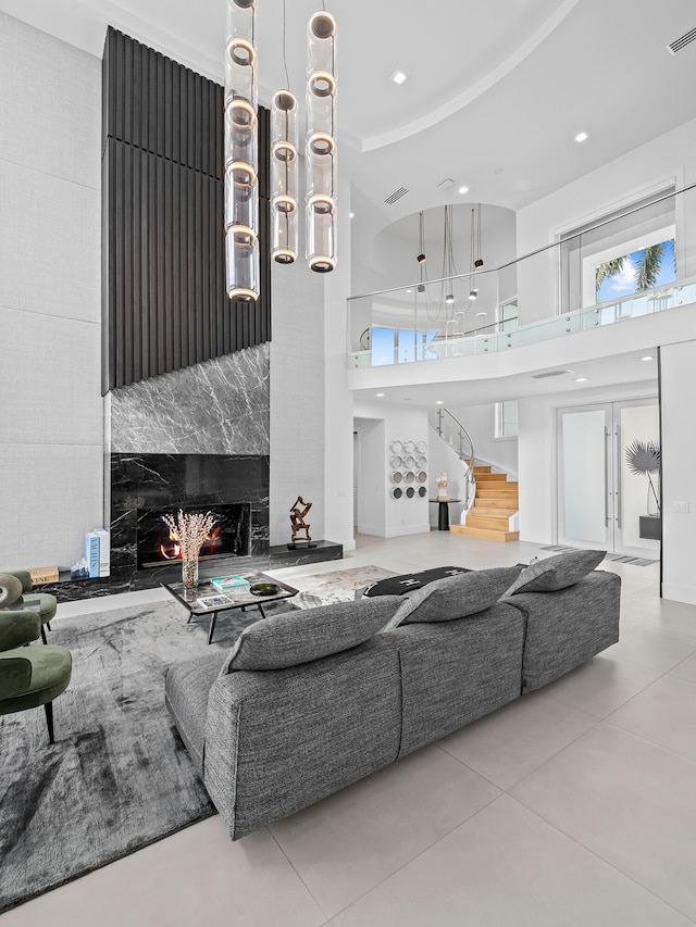 tiled living area featuring recessed lighting, a towering ceiling, a high end fireplace, stairway, and plenty of natural light