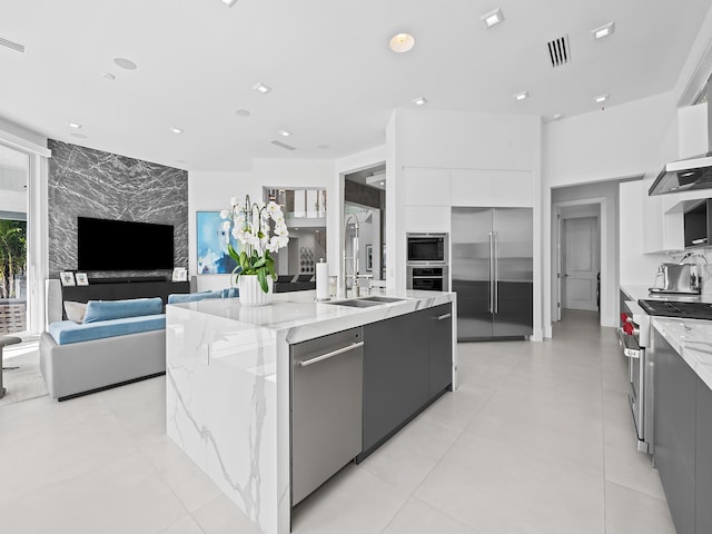 kitchen featuring built in appliances, a sink, white cabinets, a large island, and modern cabinets