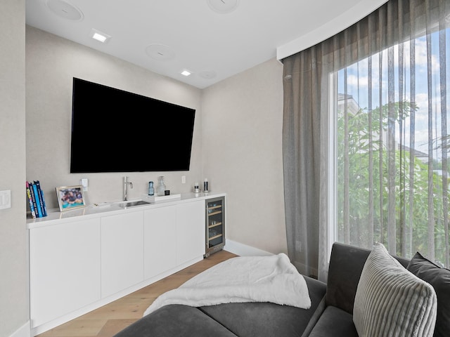 interior space with light wood-style floors, wet bar, beverage cooler, and baseboards