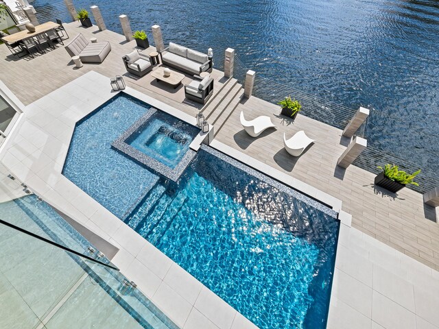 view of swimming pool with a water view, a pool with connected hot tub, and an outdoor living space