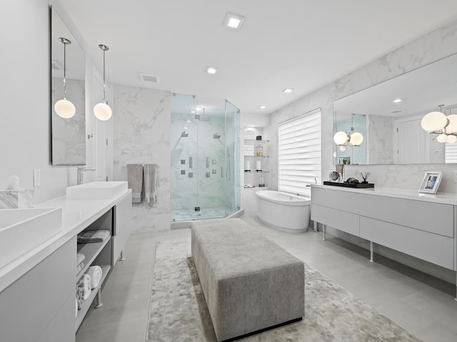 bathroom featuring tile walls, a marble finish shower, a soaking tub, visible vents, and vanity