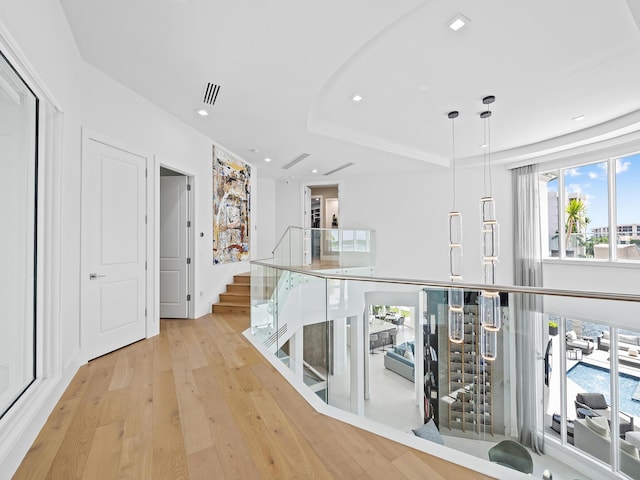 corridor featuring recessed lighting, visible vents, stairs, light wood-type flooring, and a raised ceiling