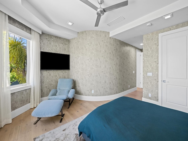 bedroom with baseboards, wood finished floors, visible vents, and wallpapered walls