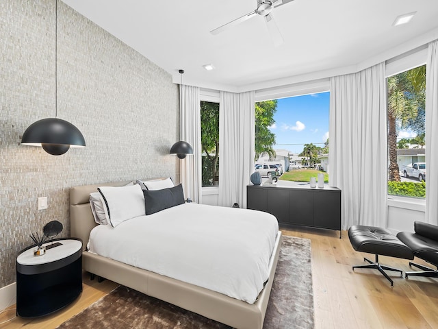 bedroom with wallpapered walls, ceiling fan, and wood finished floors