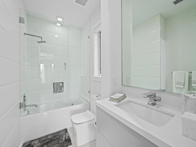 full bath featuring toilet, visible vents, bath / shower combo with glass door, and vanity