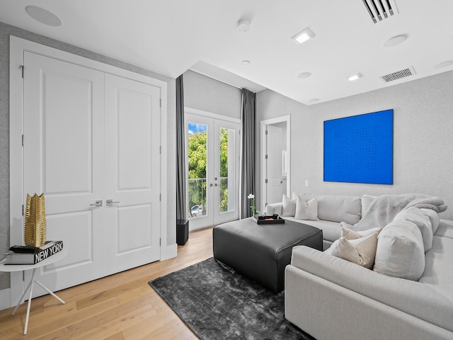 living room with light wood-style floors, french doors, and visible vents