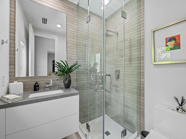 bathroom with a stall shower, visible vents, vanity, and toilet