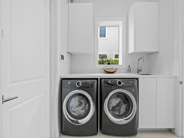 laundry area with cabinet space, washing machine and dryer, and a sink