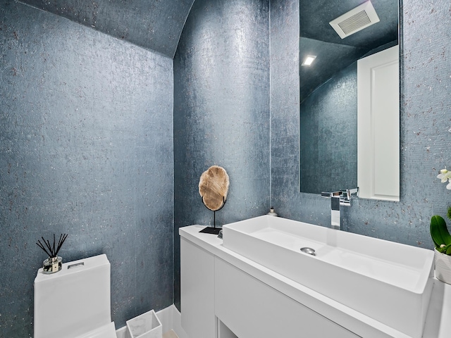 bathroom featuring visible vents, vaulted ceiling, and vanity