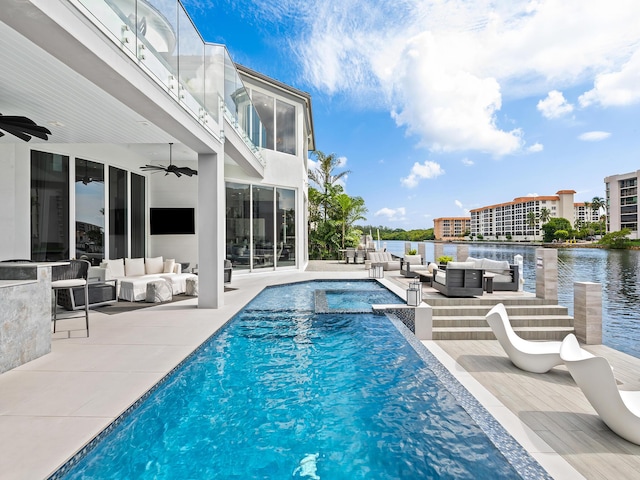 pool featuring a water view, a patio area, an outdoor living space, and a ceiling fan