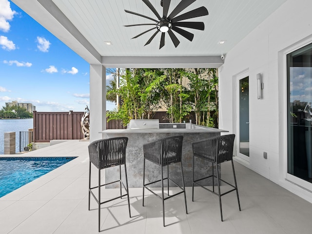 view of patio / terrace with outdoor wet bar, an outdoor pool, an outdoor kitchen, and a ceiling fan