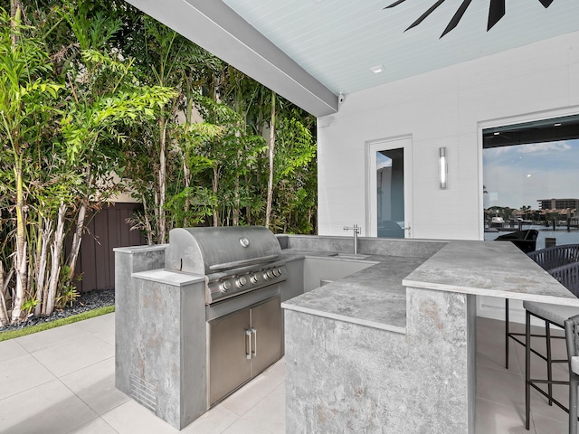 view of patio / terrace with ceiling fan, outdoor wet bar, area for grilling, fence, and grilling area