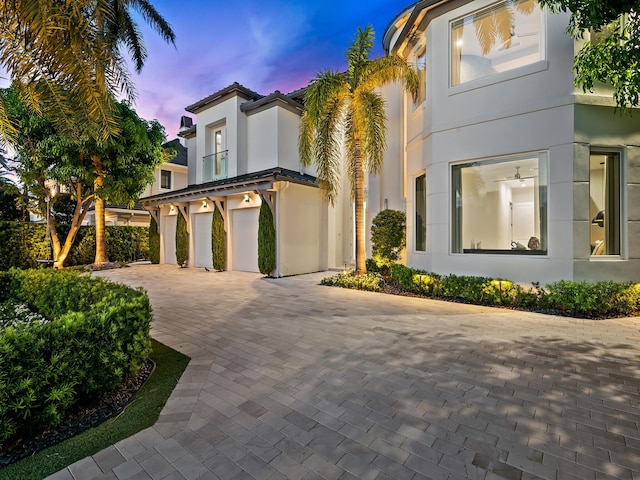 view of front facade with a garage, a tile roof, decorative driveway, and stucco siding