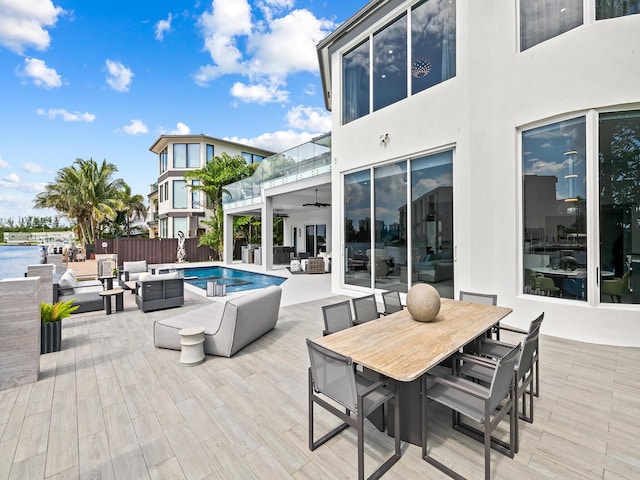 view of patio featuring ceiling fan, outdoor dining area, a deck with water view, fence, and an outdoor living space