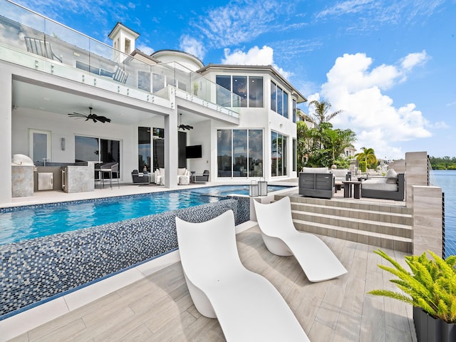 pool with a patio, ceiling fan, outdoor dry bar, exterior kitchen, and an outdoor living space