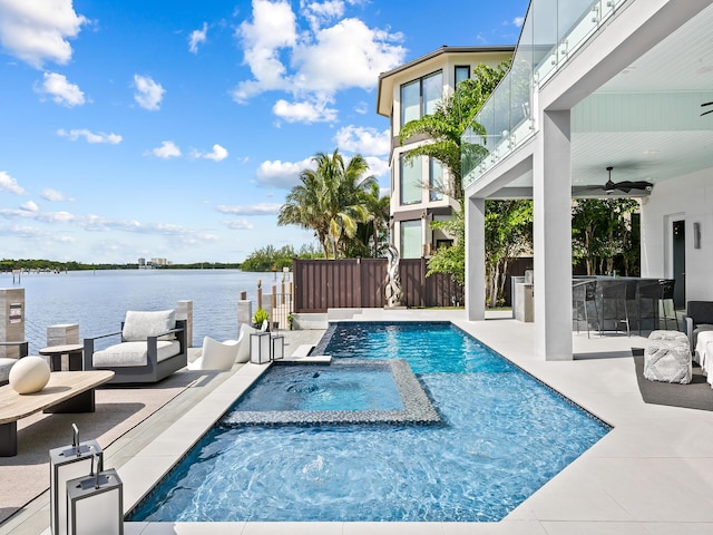 view of swimming pool with a patio, ceiling fan, outdoor dry bar, a water view, and fence