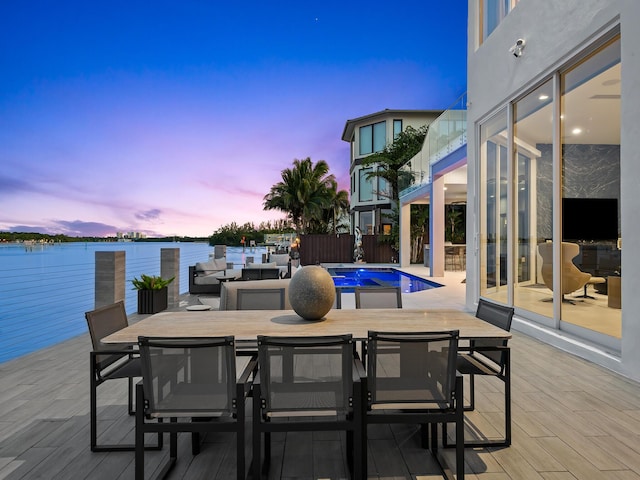 view of patio featuring outdoor dining area, a water view, an outdoor pool, and fence