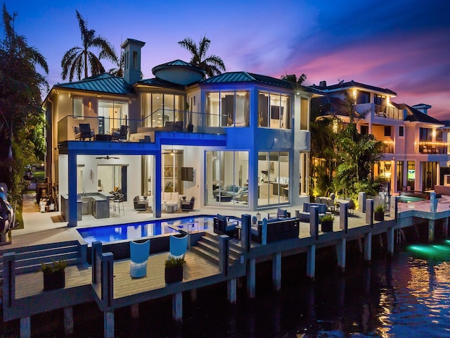 back of house featuring a balcony, metal roof, a water view, a standing seam roof, and outdoor lounge area