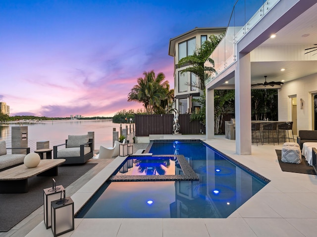 view of swimming pool with a patio, ceiling fan, outdoor dry bar, a water view, and fence