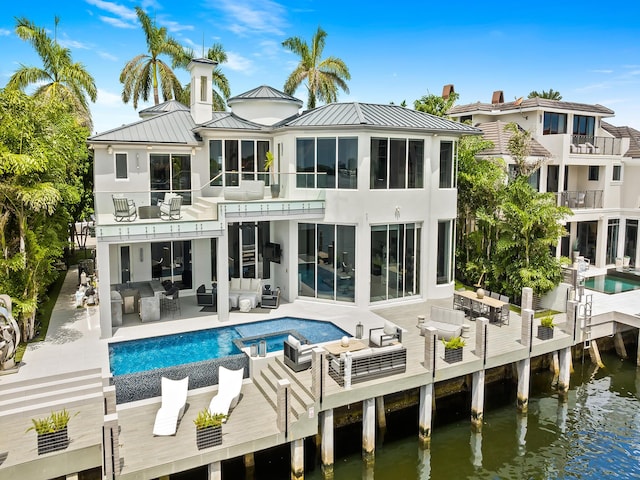 rear view of property featuring a water view, an outdoor hangout area, outdoor dining space, a standing seam roof, and a balcony