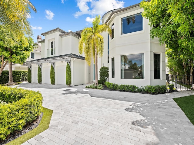 view of front of home featuring a garage, fence, decorative driveway, and stucco siding