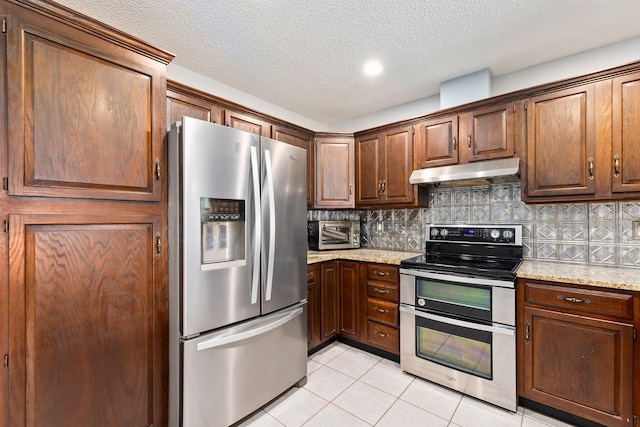 kitchen with light tile patterned flooring, appliances with stainless steel finishes, a textured ceiling, and light stone counters