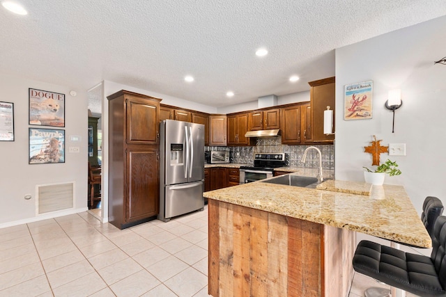 kitchen featuring appliances with stainless steel finishes, sink, light tile patterned floors, kitchen peninsula, and a textured ceiling