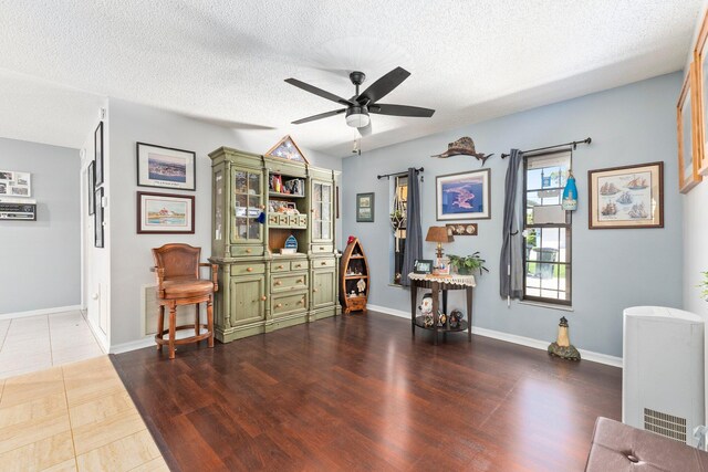 misc room with ceiling fan, dark hardwood / wood-style flooring, and a textured ceiling