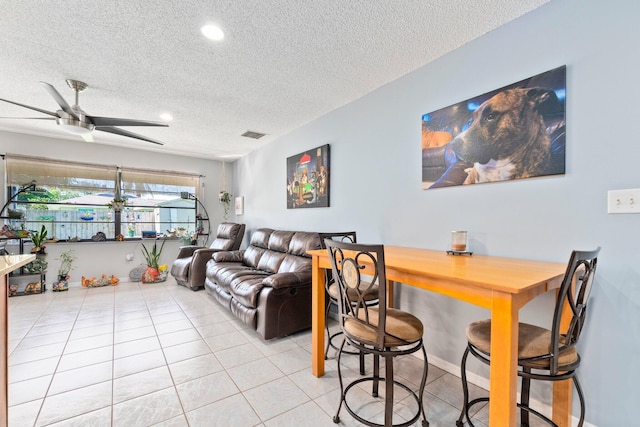 living room with ceiling fan, light tile patterned floors, and a textured ceiling