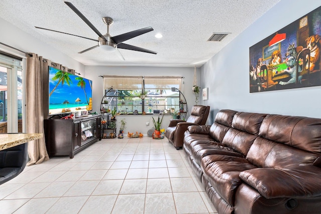 living room with ceiling fan, a textured ceiling, and light tile patterned flooring