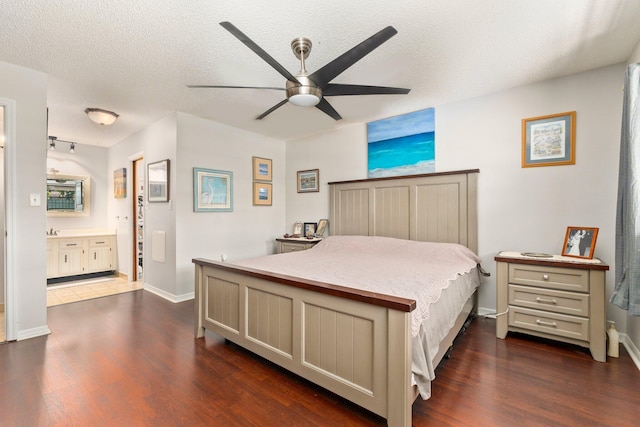 bedroom with dark wood-type flooring, ceiling fan, ensuite bath, and a textured ceiling