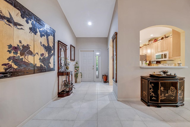 corridor featuring lofted ceiling and light tile patterned floors