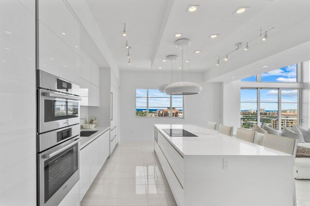 kitchen featuring a large island, white cabinets, light tile patterned floors, and double oven