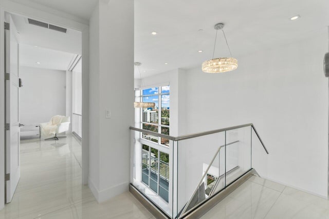 corridor with light tile patterned floors and an inviting chandelier