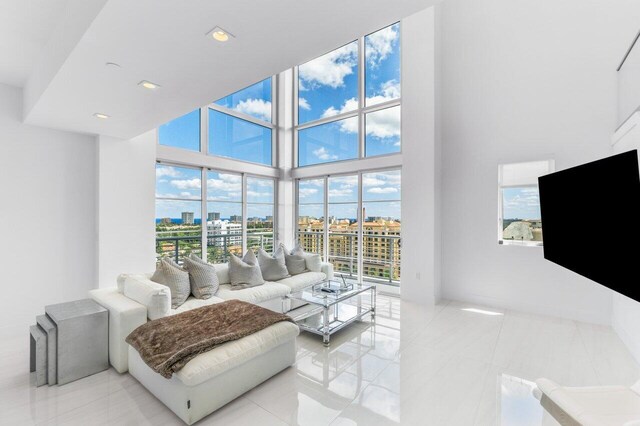 living room featuring a towering ceiling, a healthy amount of sunlight, and light tile patterned floors