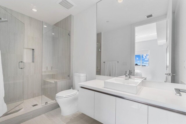 bathroom featuring tile patterned floors, vanity, walk in shower, and toilet