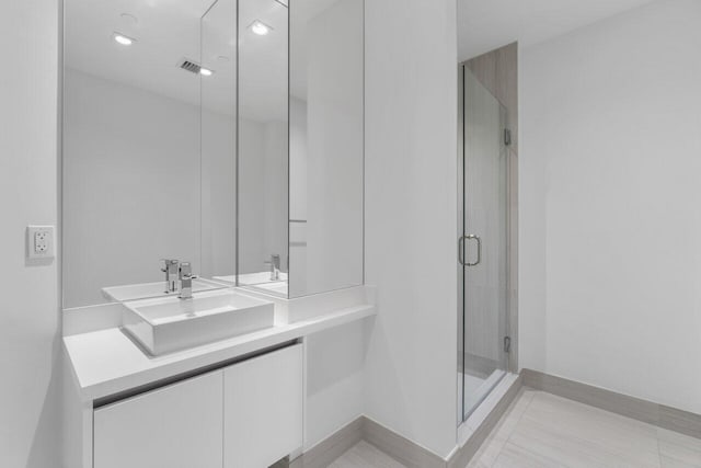 bathroom with a shower with door, vanity, and tile patterned floors