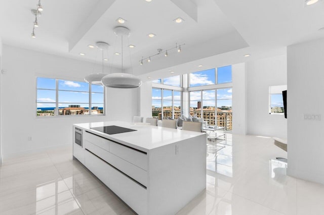 kitchen with a kitchen island, white cabinets, track lighting, decorative light fixtures, and light tile patterned flooring