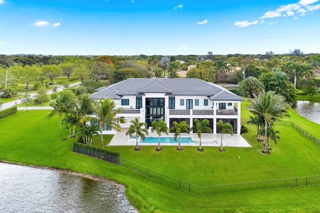 rear view of property featuring a patio, a balcony, a fenced backyard, a water view, and a yard