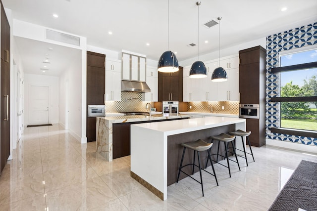 kitchen featuring pendant lighting, plenty of natural light, a breakfast bar area, and white oven