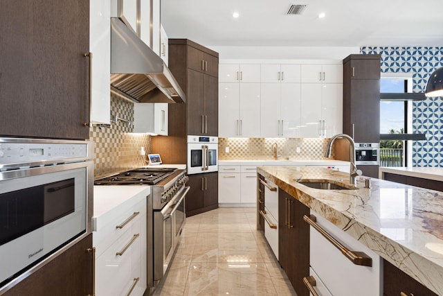 kitchen with ventilation hood, white cabinets, sink, and appliances with stainless steel finishes