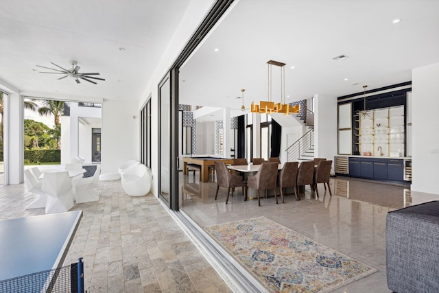 living room featuring ceiling fan, sink, and a wall of windows