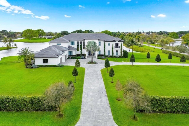 view of front of home with a water view, a front lawn, and decorative driveway