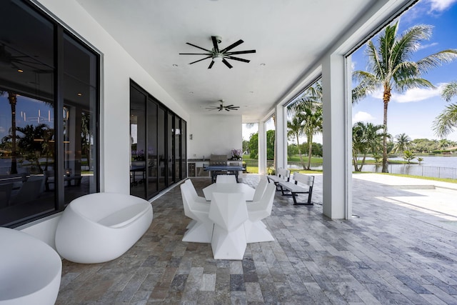 view of patio with area for grilling, ceiling fan, and a water view