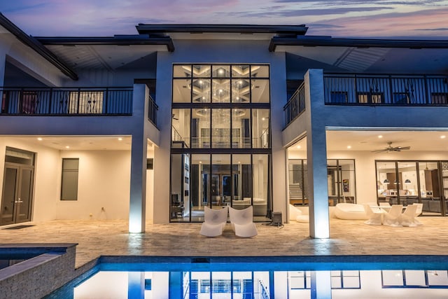 back house at dusk with a patio and ceiling fan