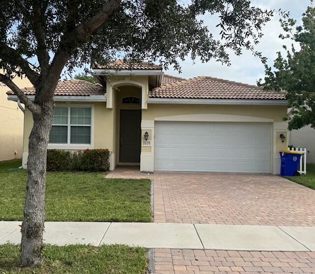 2609 SW Gallery Cir, Palm City, FL 34990 - mediterranean / spanish house with decorative driveway, a tile roof, a front yard, a garage, and stucco siding