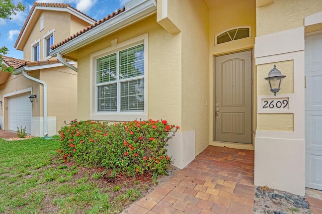 2609 SW Gallery Cir, Palm City, FL 34990 - view of exterior entry featuring stucco siding, a garage, and a tile roof